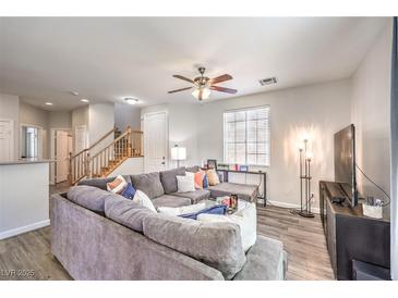 Bright living room with a plush gray sectional sofa, ceiling fan, and wood-look flooring at 10636 Colter Bay Ct, Las Vegas, NV 89129