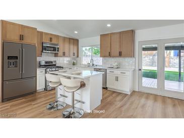 Bright kitchen features stainless steel appliances, white countertops, and a center island with bar seating at 2529 Indian Sage Way, Las Vegas, NV 89108