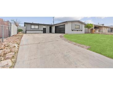 Charming single-story home with black and white accents, a driveway, and a well-manicured lawn at 6437 Burgundy Way, Las Vegas, NV 89107