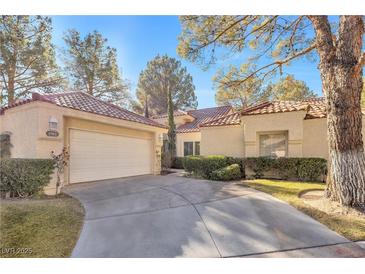 Charming single-story home with a well-manicured lawn, mature trees, and a two-car garage at 6961 Emerald Springs Ln, Las Vegas, NV 89113