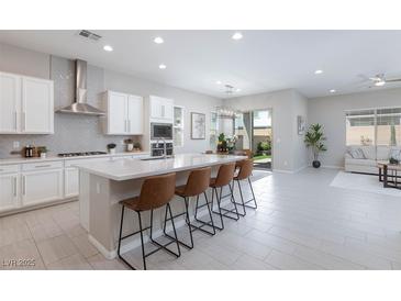 Bright, open kitchen featuring a large island with seating, modern appliances, and seamless flow to the living area at 10251 Tiger Milkweed St, Las Vegas, NV 89141