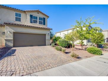 Two-story home featuring a two-car garage, landscaped front yard, and a brick-paved driveway at 104 Pollentia Ave, North Las Vegas, NV 89084