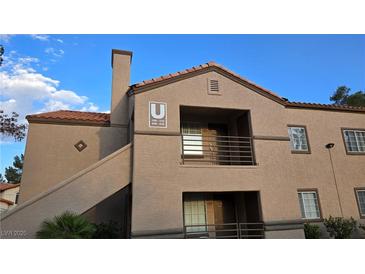 Two-story condo building with a terra cotta roof and private balconies under a blue sky in a well-maintained community at 9070 Spring Mountain Rd # 209, Las Vegas, NV 89117