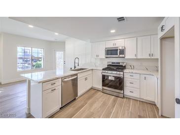 Bright kitchen features white cabinets, stainless appliances, quartz countertops and an island with a sink at 9303 Gilcrease Ave # 1243, Las Vegas, NV 89149