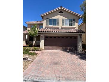 Two-story home featuring a tile roof and a brick paved driveway leading to a two car garage at 10974 Fintry Hills St, Las Vegas, NV 89141