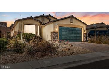 Charming single-story home featuring a two-car garage, stone accents, and desert landscaping at 2128 Delmar Farms Ct, Laughlin, NV 89029