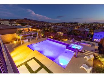 Inviting pool and spa with an outdoor kitchen, set against a picturesque mountain and city backdrop at twilight at 2153 King Crest Ct, Henderson, NV 89052