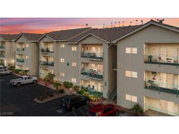 Inviting condo building with tan siding and balconies with decorative railings, surrounded by lush greenery and ample parking at 3550 Bay Sands Dr # 2101, Laughlin, NV 89029
