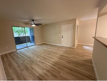 Bright living room features wood-look floors, balcony access, and a modern ceiling fan at 555 E Silverado Ranch Blvd # 1034, Las Vegas, NV 89183