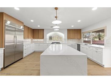 Bright kitchen features large island, stainless steel refrigerator, and ample countertop space at 7616 Gossamer Wind St, Las Vegas, NV 89139