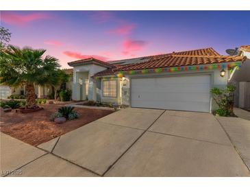 Charming single-story home featuring a red tile roof, two-car garage, and desert landscaping at sunset at 7874 Trail Boss Ct, Las Vegas, NV 89113