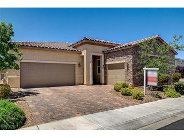 Charming single-story home features a tiled roof, desert landscaping, and a brick-paved driveway leading to a two-car garage at 2425 Amatrice St, Henderson, NV 89044