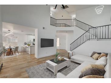 Bright, open-concept living room featuring a staircase and modern furnishings, flowing into the dining and kitchen area at 5466 Silverheart Ave, Las Vegas, NV 89142