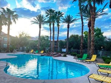 Beautiful community pool surrounded by palm trees and lounge chairs at 8000 Badura Ave # 2009, Las Vegas, NV 89113