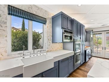 Bright kitchen with marble countertops, oversized window with a view, and custom blue cabinets at 11578 Suburban Rd, Las Vegas, NV 89135