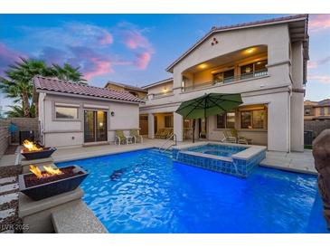 Inviting pool area with spa, fire bowls, and umbrella, creating a luxurious backyard retreat at 12219 Crystal Shore Ave, Las Vegas, NV 89138