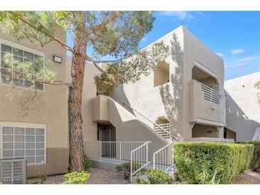 Two-story condo showcasing landscaped grounds, and stairs leading up to private balconies on a sunny day at 1900 Mountain Hills Ct # 203, Las Vegas, NV 89128