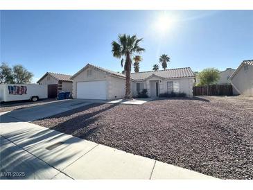 Single story home featuring desert landscaping, a two car garage, and a tall palm tree at 4651 Wild Oak Way, North Las Vegas, NV 89031