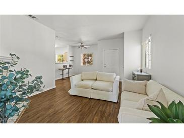 Bright living room with wood floors, neutral walls and white sofas adjacent to a breakfast bar with stools at 5250 S Rainbow Blvd # 2070, Las Vegas, NV 89118