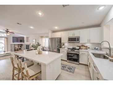 Modern kitchen featuring white cabinets, stainless steel appliances, and a large center island with seating at 8136 Shady Glen Ave, Las Vegas, NV 89131
