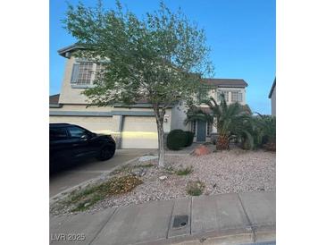 Charming two-story home boasts a landscaped front yard, mature tree, two-car garage, and inviting curb appeal at 82 Scorpios Island St, Henderson, NV 89012
