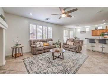 Inviting living room with neutral tones, area rug, ceiling fan, and comfortable seating at 10294 Running Falls St, Las Vegas, NV 89178