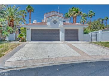 Two-car garage with a patterned concrete driveway and mature palm trees at 217 Windsong Dr, Henderson, NV 89074