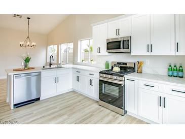 Bright kitchen features stainless steel appliances, white cabinets, and light wood flooring at 6124 Desert Haven Rd, Las Vegas, NV 89130