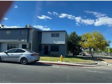 Two-story townhouse with gray siding, well-kept lawn, and mature trees against a blue sky at 816 E Nelson Ave # F, North Las Vegas, NV 89030