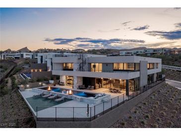 An amazing rear exterior with a modern design including a pool, outdoor seating and views of mountains and city lights at 53 Falling Ridge Ln, Henderson, NV 89011