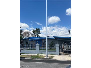 Charming single-story home featuring a blue accent roof and a decorative wrought iron fence at 1708 Weeping Willow Ln, Las Vegas, NV 89104