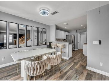 Bright dining area with modern table, chairs, and decorative mirrors, adjacent to the kitchen with wood floors at 5024 Starfinder Ave, Las Vegas, NV 89108