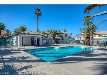 Community pool with clear blue water and shade, surrounded by palm trees and well-maintained landscaping at 5024 Starfinder Ave, Las Vegas, NV 89108