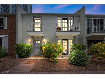Inviting townhome featuring dual balconies, a brick pathway, blossoming shrubs, and exterior lighting at 530 Tam O Shanter, Las Vegas, NV 89109