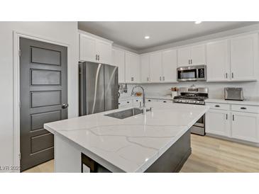 Modern kitchen featuring white cabinets, stainless steel appliances, and an island with a white countertop at 7122 Red Gulch St, North Las Vegas, NV 89084