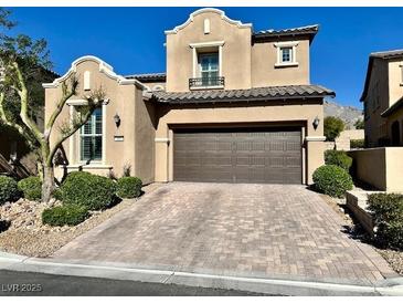 Charming two-story home with a brown garage door, landscaped yard and brick driveway at , Las Vegas, NV 89138