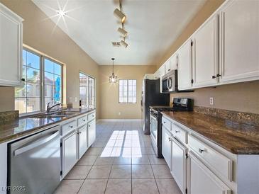 Bright kitchen features white cabinetry, tiled floors, stainless steel appliances, and ample counter space at 1851 Hillpointe Rd # 2124, Henderson, NV 89074