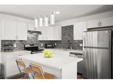 Modern kitchen features stainless steel appliances, center island, stone countertops, and attractive backsplash at 3208 Alcoa Ave, Las Vegas, NV 89102
