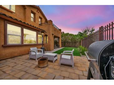 This cozy backyard has a barbecue, seating, and a patch of artificial grass at 617 Apricot Rose Pl, Las Vegas, NV 89138