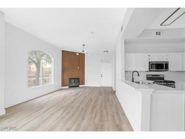 Bright living room featuring wood-look flooring, modern fireplace, and an open layout connected to the kitchen at 700 Carnegie St # 3913, Henderson, NV 89052