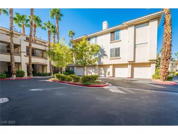Condominium building with attached garages, beautiful landscaping, and palm trees, perfect for low-maintenance living at 7189 S Durango Dr # 203, Las Vegas, NV 89113