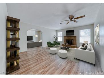Bright living room featuring a brick fireplace, modern furniture, and wood-look floors at 729 Scottsdale St, Henderson, NV 89002