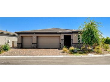 Beautiful single-story home featuring a three-car garage and landscaped front yard with a brick-paved driveway at 21 Reverie Heights Ave, Henderson, NV 89011