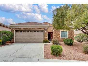 Charming single-story home featuring a two-car garage, stone accents, and a well-maintained front yard with lush landscaping at 2343 Galilean Moon St, Henderson, NV 89044