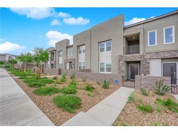 Modern townhome showcasing a landscaped front yard and neutral stucco facade with stone accents at 334 Laurel Peak Dr, Henderson, NV 89015