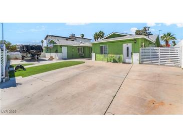 Charming green home featuring a spacious driveway and secured by a white horizontal slat fence at 4406 Parkchester Cir, Las Vegas, NV 89108