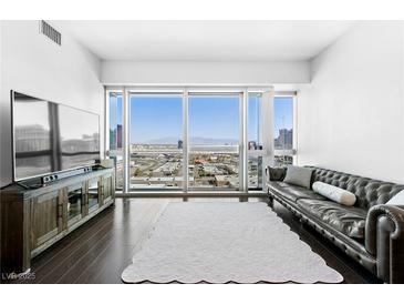 Bright living room features a leather sofa, sleek TV console, and expansive city views at 4471 Dean Martin Dr # 1502, Las Vegas, NV 89103