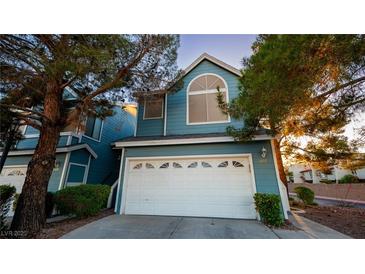 Charming two-story home with a white garage door and light blue exterior with mature landscaping at 3217 Symphony Dr, Las Vegas, NV 89146