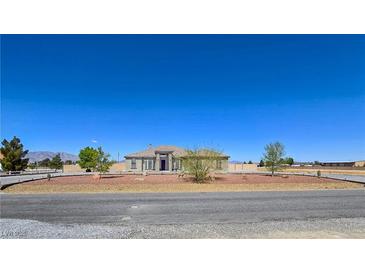 Expansive single-story home showcasing desert landscaping, circular driveway, and a symmetrical facade under a clear blue sky at 3780 Shawnee Ave, Pahrump, NV 89048