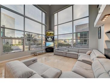 Bright, open living room with floor-to-ceiling windows and a large gray sectional sofa at 4515 Dean Martin Dr # 200, Las Vegas, NV 89103